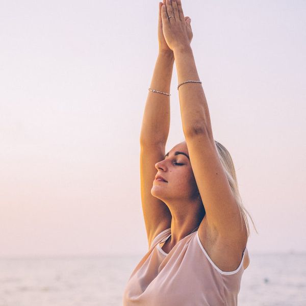 Person meditating peacefully on a beach at sunrise, embodying tranquility.